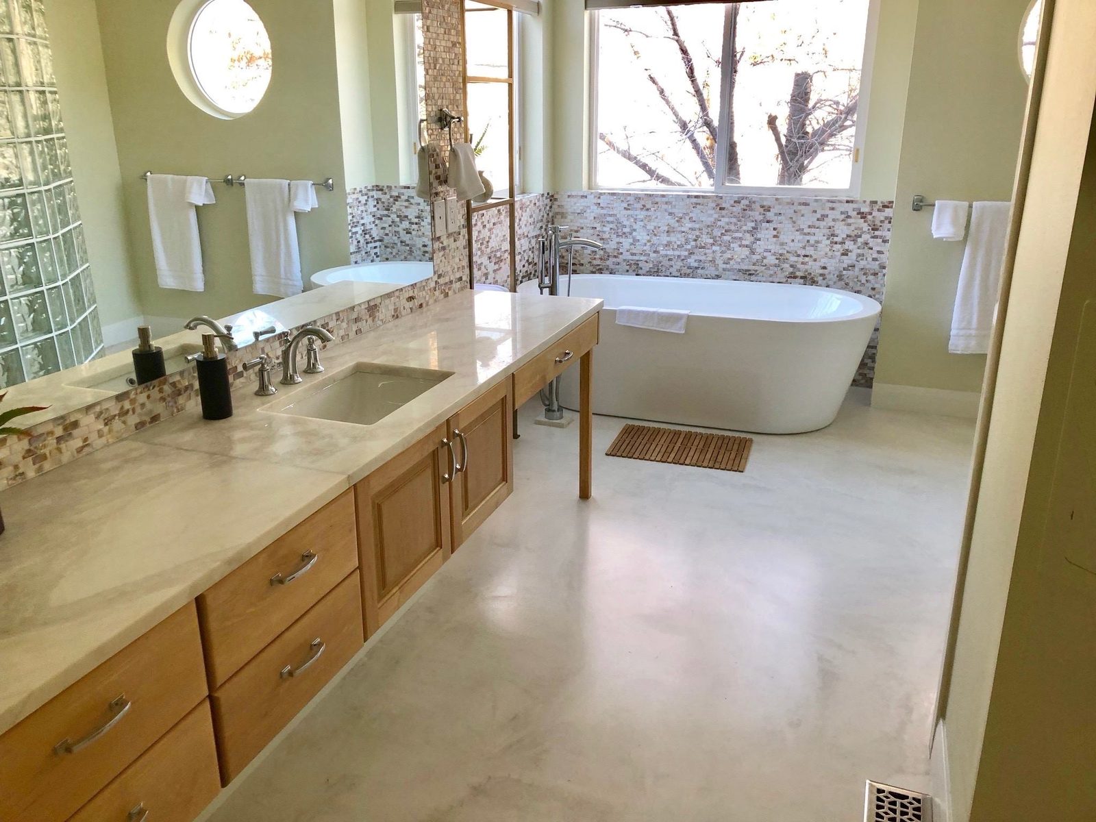 Primary bathroom in Nashville with a continuous hand-troweled microcement floor and freestanding tub