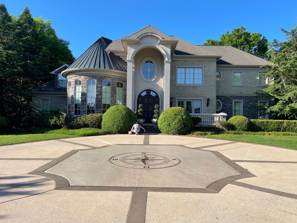 Circular motor court at a Brentwood estate finished with a compass rose inlay picked out in two tones against a darker border band