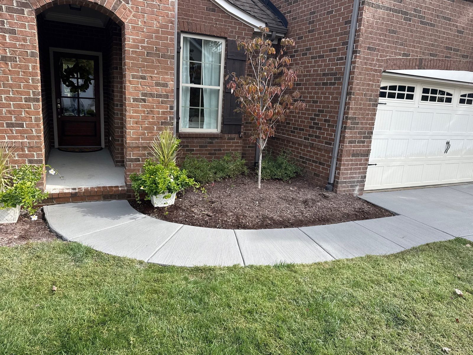 Curved front walkway in Westhaven with a fresh broom finish and clean mulch-bed edging